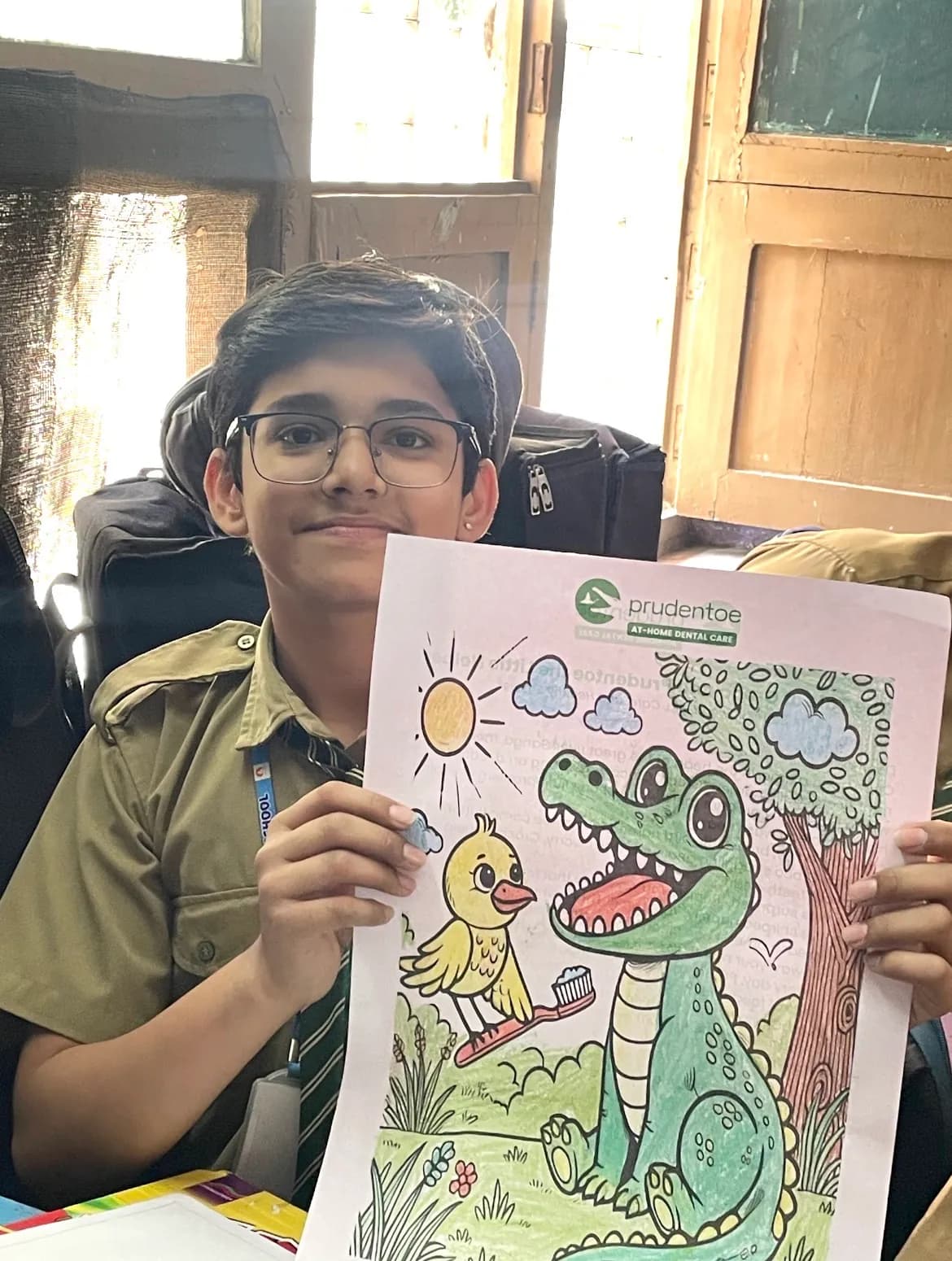 School child happily holding a Prudentoe branded dental awareness coloring sheet in Hyderabad